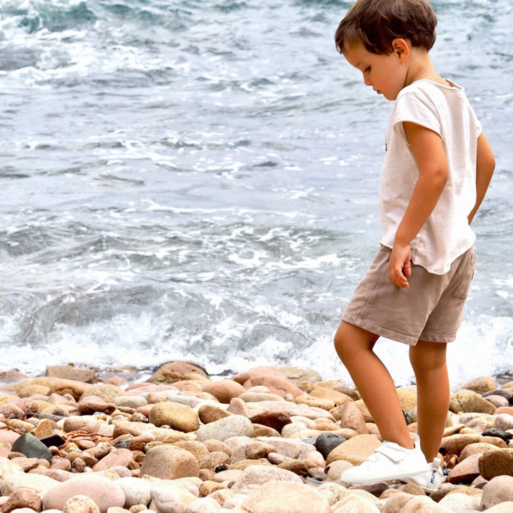 niño caminando por las piedras en la playa con las terre blancas